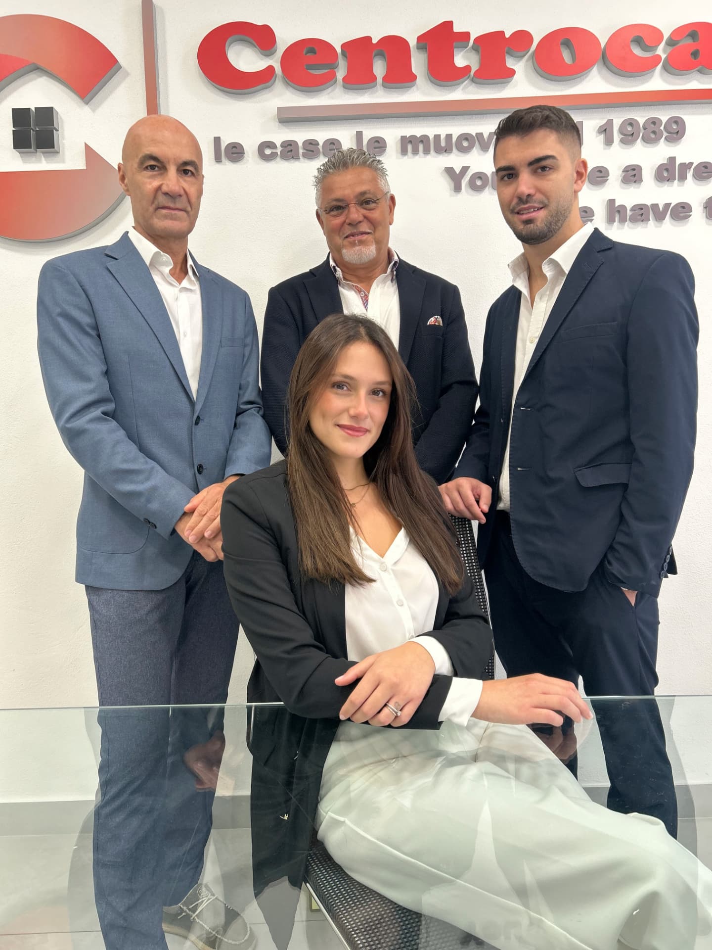 Il team CENTROCASA davanti alla parete con logo dell'agenzia a Magenta